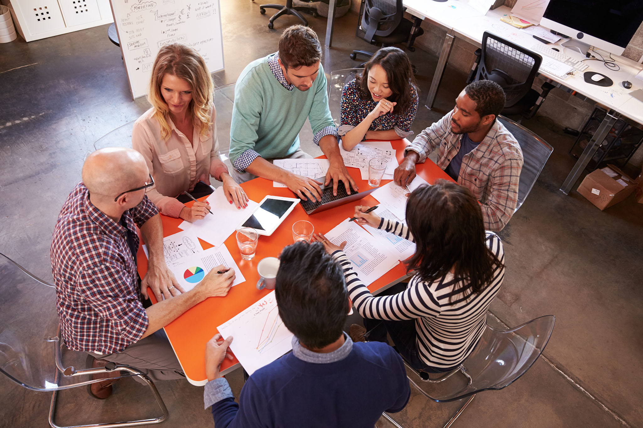 Overhead View Of Designers Having Meeting Around Table